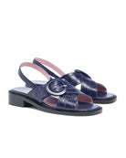 Navy blue sandals with a circular buckle on a white background