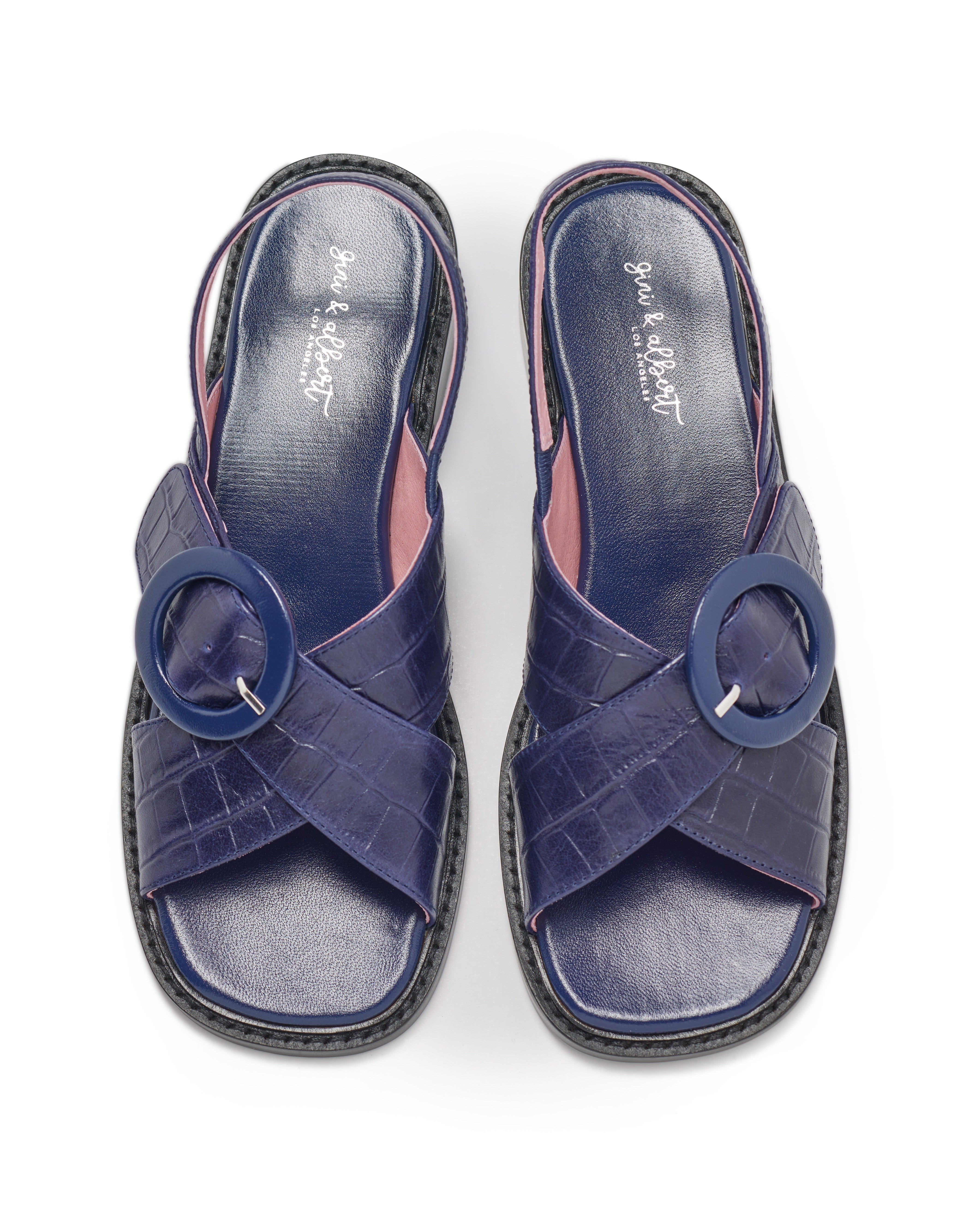 Pair of blue sandals with circular straps on a white background