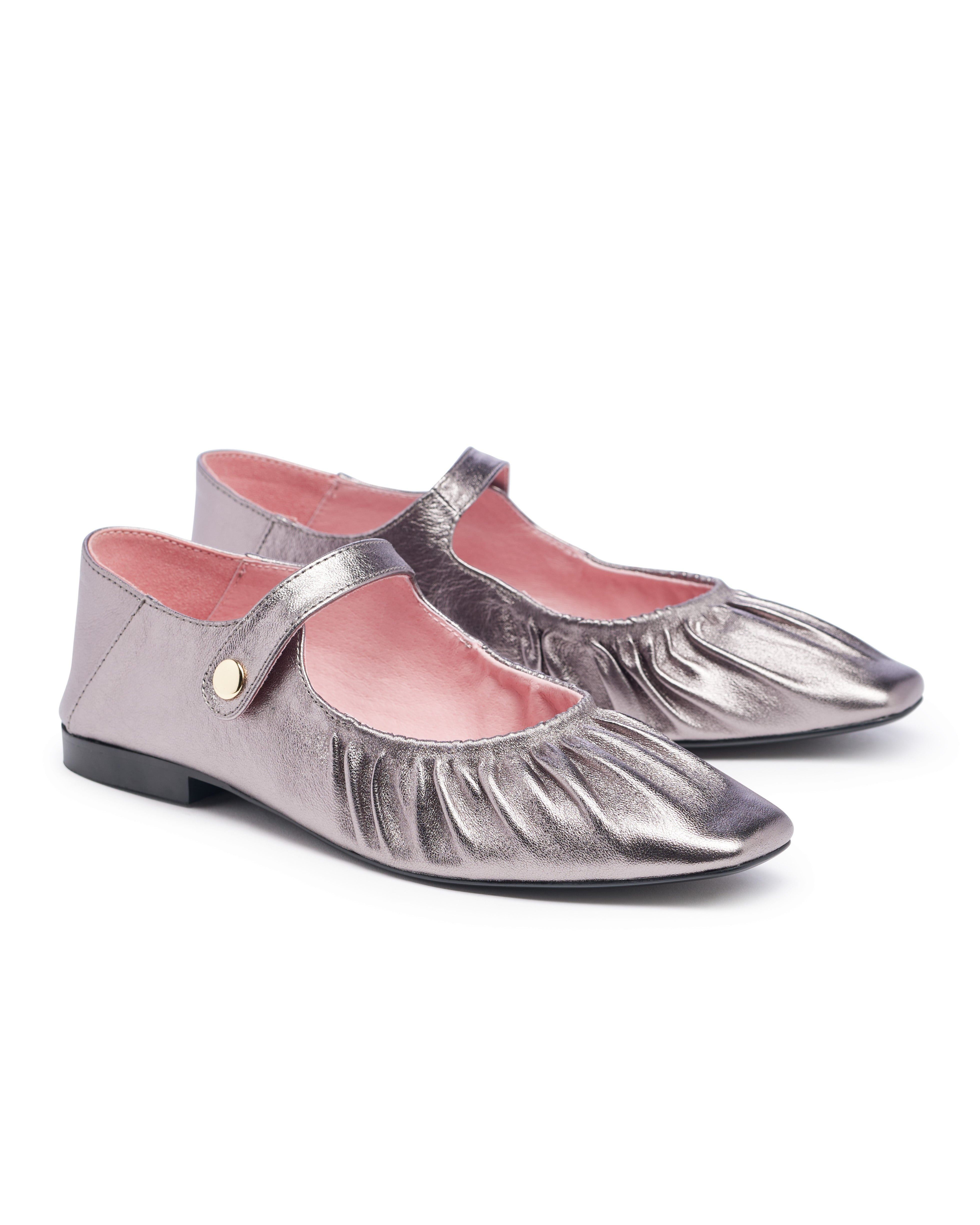 Pair of silver metallic shoes with pink lining on a white background