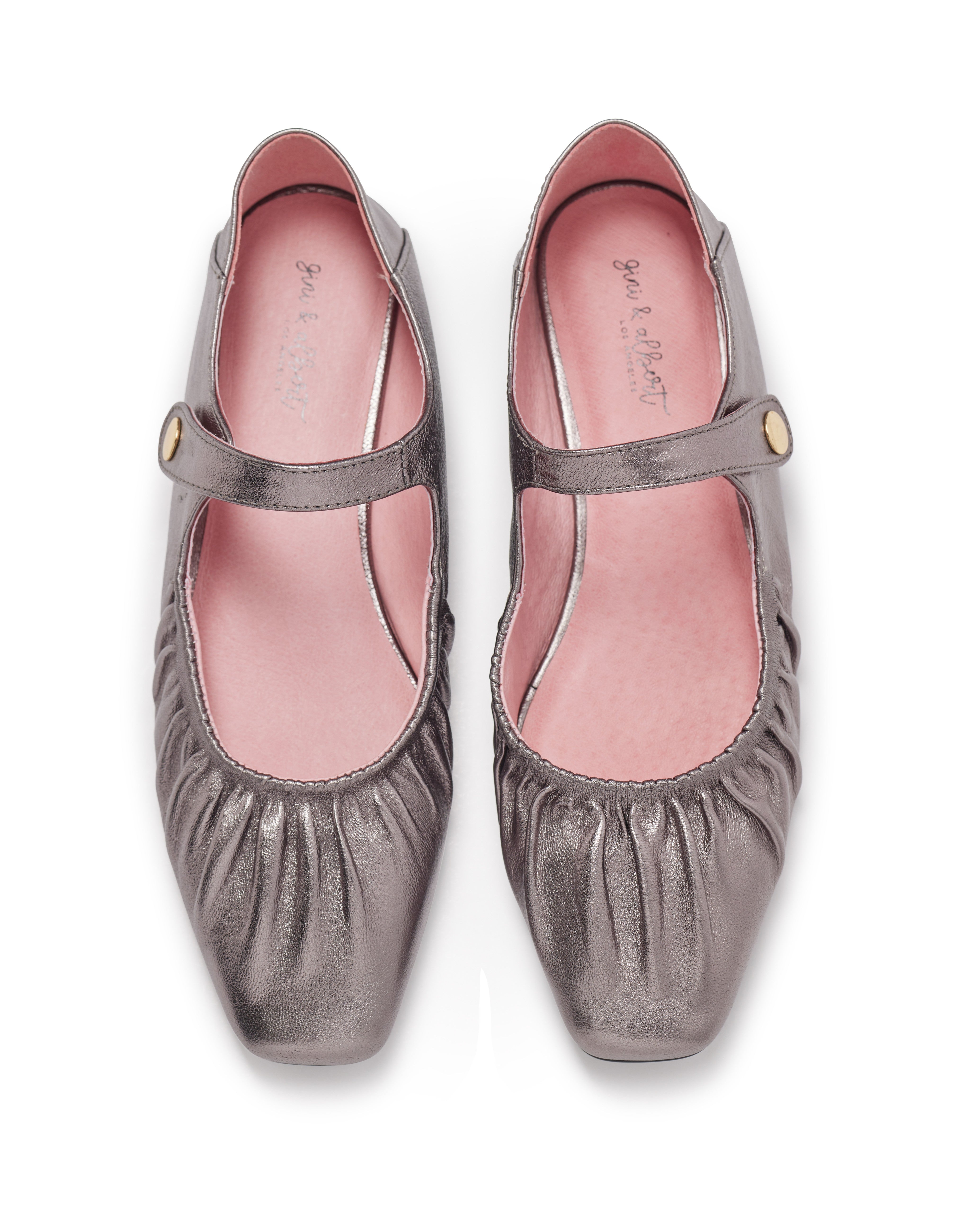 Pair of metallic gray shoes with a strap on a white background